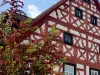 Fachwerkhaus mit Baum davor, der rote Früchte trägt